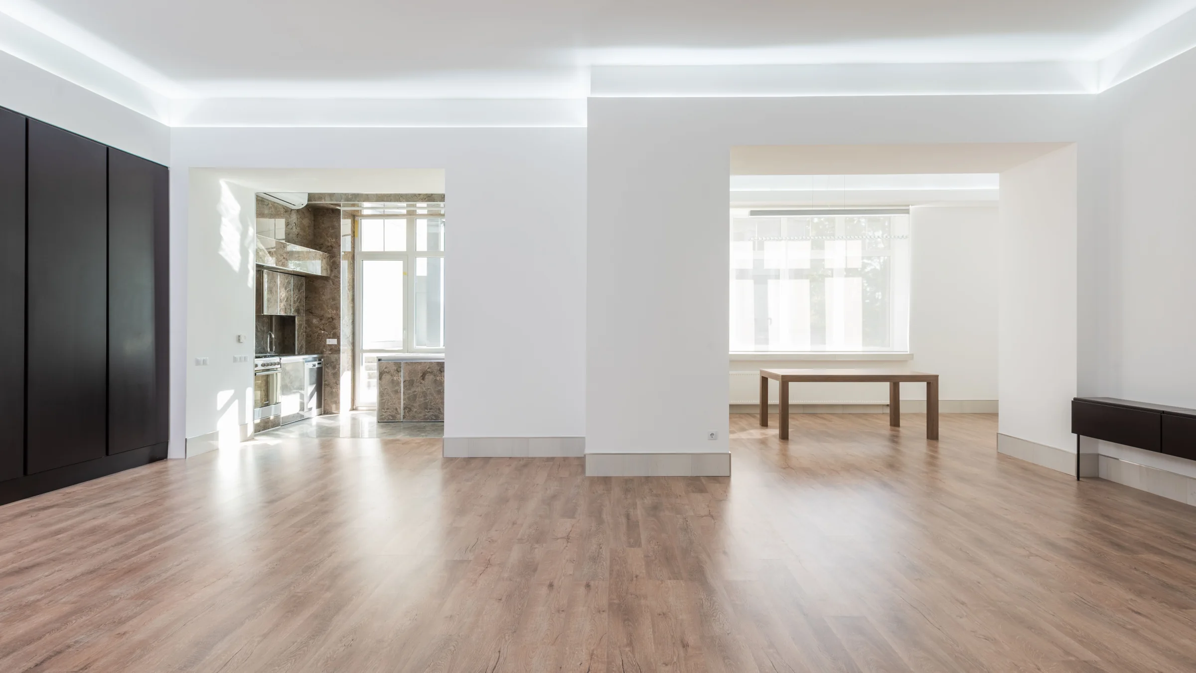 Großzügige, leere Wohnung nach der Modernisierung mit indirekter Deckenbeleuchtung, hellen Wänden und Boden in Holzoptik